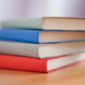 Pila di libri di testo con copertine colorate di grigio, blu, rosso